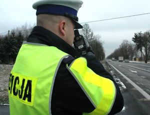 policjant z drogówki mierzy miernikiem prędkość pojazdów