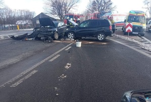 dwa rozbite auta koloru ciemnego stojące na drodze za nimi dwa ambulansy i dwa pojazdy strażackie