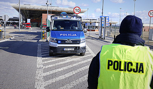 W pierwszym planie zdjęcia stoi policjant na przejściu granicznym Dołhobyczowie. W drugim planie zdjęcia radiowóz oznakowany z napisem policja
