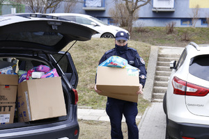 Policjant niesie dary dla uchodźców.