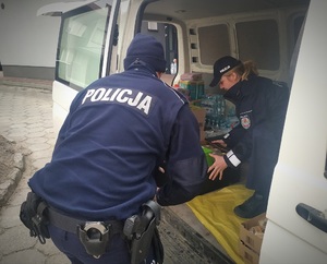 Policjanci rozładowują z busa dary