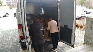 dwie kobiety wypakowują dary z busa