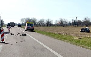 miejsce zdarzenia drogowego, z prawej strony na polu obok jezdni widać rozbity pojazd