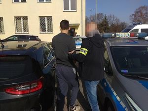 policjant prowadzi zatrzymanego do samochodu