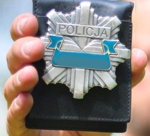 policjant trzyma w reku odznakę