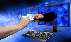 Grafika oszustw internetowych. Ręka wychodząca z komputera chwyta kartę bankomatową