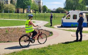 rowerzystka pokonuje trasę miasteczka ruchu drogowego pod nadzorem policjantów