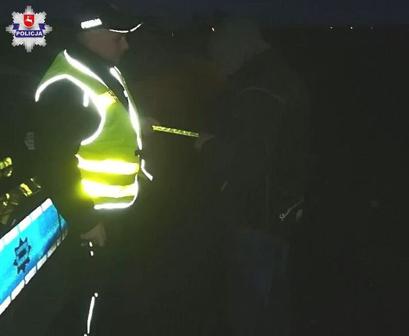 policjant ruchu drogowego w odblaskowej kamizelce stoi przy radiowozie