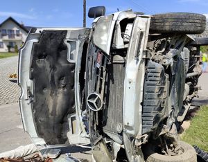 biały bus przewrócony na bok. Widok z przodu