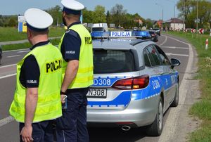 policjanci z drogówki stoją przy radiowozie