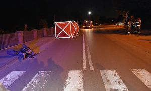 miejsce wypadku, motocykl leżący na chodniku, w tle widać czerwony parawan