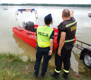 zdjęcie przedstawia policjantkę i strażaka nad zbiornikiem wodnym w Firleju