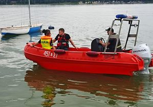 zdjęcie przedstawia policjantkę i dwóch strażaków na łodzie na zbiorniku Firlej