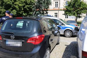 samochód pijanego kierowcy, obok stoją policjanci, a w tle widać radiowóz