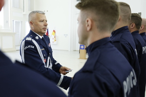 Komendant Wojewódzki Policji w Lublinie wręcza legitymacje nowemu policjantowi i gratuluje wstąpienia do służby.