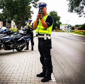 policjant kontroluje prędkość, w tle motocykl
