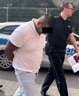 policjant prowadzi zatrzymanego