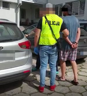 policjant prowadzi zatrzymanego do pojazdu
