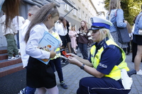 Policjantka rozdaje dzieciom odblaski.