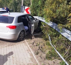 na zdjęciu na pierwszym planie, samochód marki Audi, po prawej uszkodzona barierka ochronna w tle policjant przy radiowozie