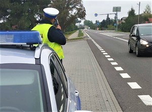 policjant przy drodze mierzy prędkość pojazdu