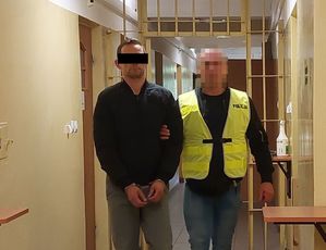 policjant kryminalny prowadzi korytarzem komendy zatrzymanego mężczyznę