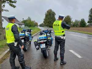 policjanci podczas patrolu na drodze. W tle motocykle