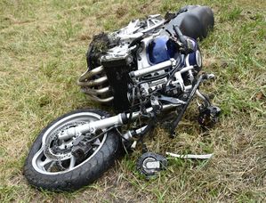 Uszkodzony motocykl leży na trawiastym poboczu