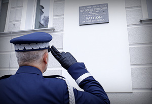 komendant wojewódzki oddaje hołd przed tablicą Naszego Patrona