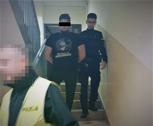 zatrzymany mężczyzna na schodach, obok policjant