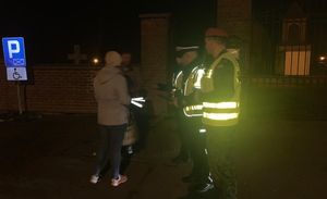 policjanci rozdają odblaski pod cmentarzem