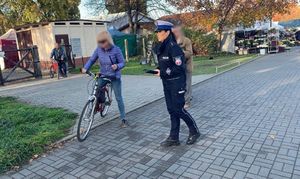 policjantka rozdaje odblaski pod cmentarzem rowerzystce