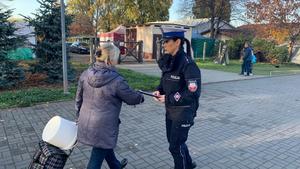 policjantka rozdająca odblaski pod cmentarzem