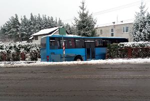 Autobus po kolizji, który uderzył w płot na ośnieżonej drodze