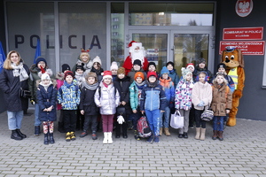 Grupowe zdjęcie dzieci z Mikołajem i inspektorem Frankiem przy Komisariacie Szóstym policji w Lublinie.