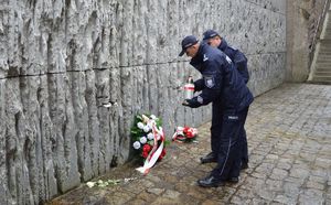 komendanci tomaszowskiej policji zapalają znicz pod pomnikiem w Bełżcu