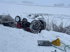 ciągnik rolniczy leżący do góry kołami w śniegu