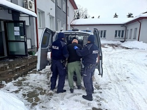 policjanci doprowadzają zatrzymanego do radiowozu