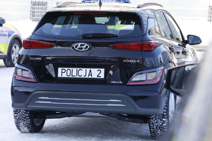 Zdjęcie przedstawia tył nowego nieoznakowanego radiowozy Hyundai Kona Electric koloru czarnego.