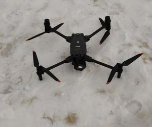 na zdjęciu dron leżący na śniegu gotowy do lotu
