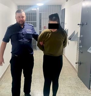 policjant prowadzi druga zatrzymaną kobietę w sprawie rozboju