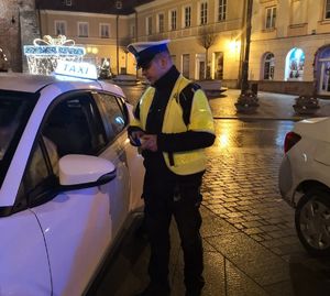policjant kontroluje taksówkę