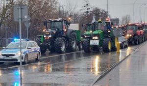 radiowóz, za nim jada ciągniki rolnicze