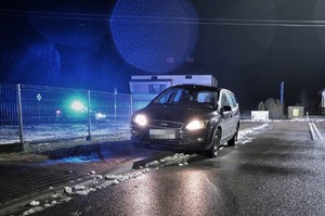 stojący na drodze samochód marki Ford Focus, w tle radiowóz z włączonymi światłami uprzywilejowania
