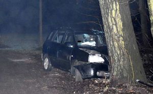 Rozbite auto na łuku drogi stoi przy drzewach