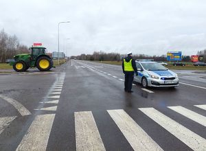 policjant, radiowóz na drodze i ciągnik rolniczy