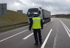 policjant na drodze, przed nim ciężarówka