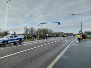 policyjny radiowóz na tle protestujących rolników