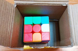 na zdjęciu kolorowa Kostka Rubika w papierowym pudełku