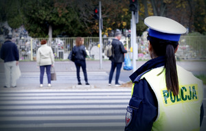 Policjantka patrzy na pieszy przechodzących przez  przejście dla pieszych.